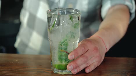 process of preparing a cocktail. mojito cocktail with lemon and mint on the bar. close-up