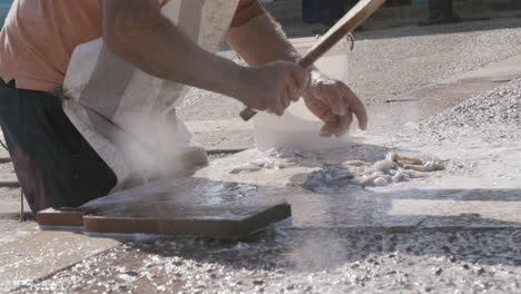 slow motion footage of a man smashing an octopus with a paddle with splatter flying up and hitting the lens