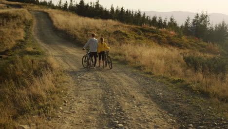 man and woman with bikes going on road