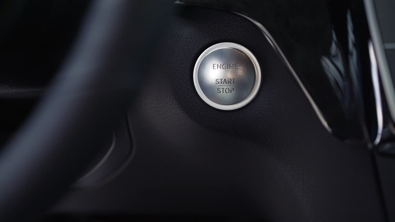 persona presionando el botón de arranque del motor del coche