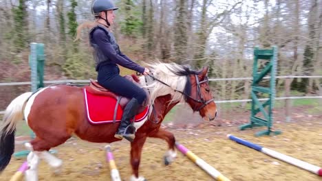 female jockey training her pony in the paddock, galloping over obstacles