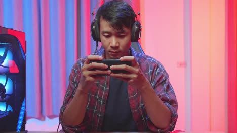 man playing mobile game in a colorful gaming setup