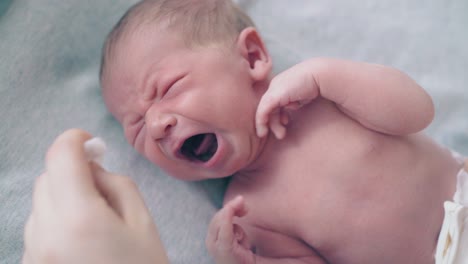 infant-boy-with-short-fair-hair-lies-on-little-bed-and-cries