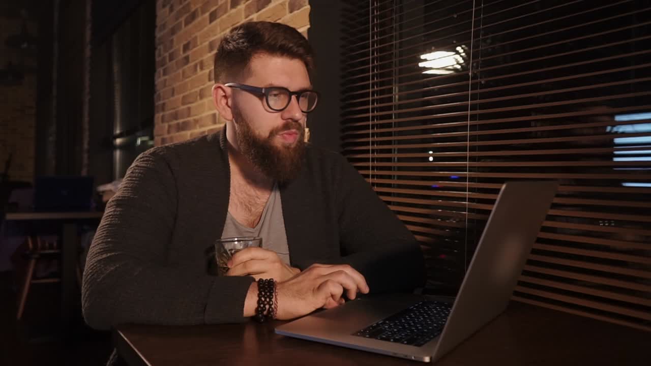hombre trabajando en una computadora portátil en un café por la noche