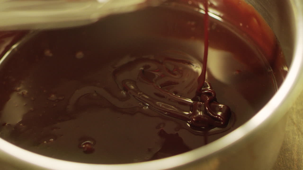 Mixing liquid chocolate with whisk in slow motion. Closeup liquid hot chocolate.