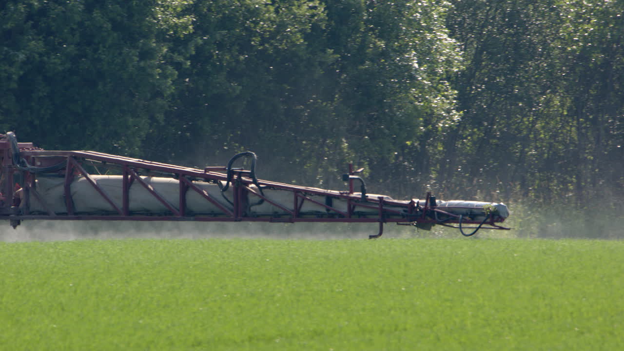 cultivos en tierras de cultivo siendo rociados por el brazo del tractor rociador, tele disparo
