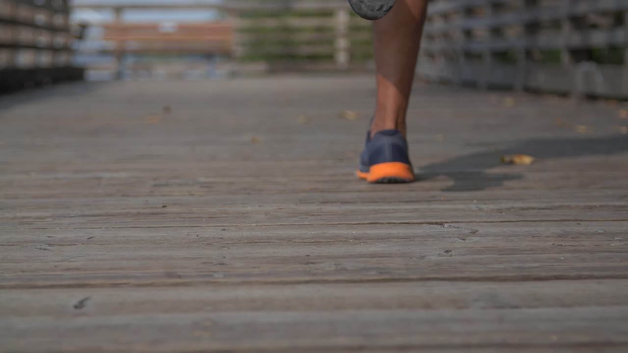 corredor profesional corriendo rápido en una cubierta de madera en una suave toma de seguimiento en cámara lenta