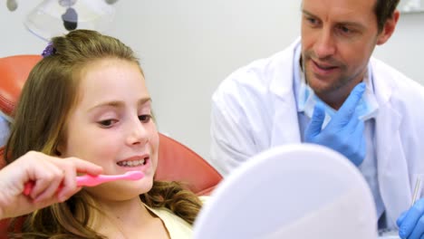 dentista enseñando a una chica a cepillarse los dientes