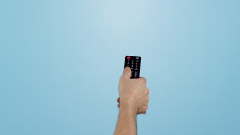 mano, el control remoto y el cambio de canales en la televisión