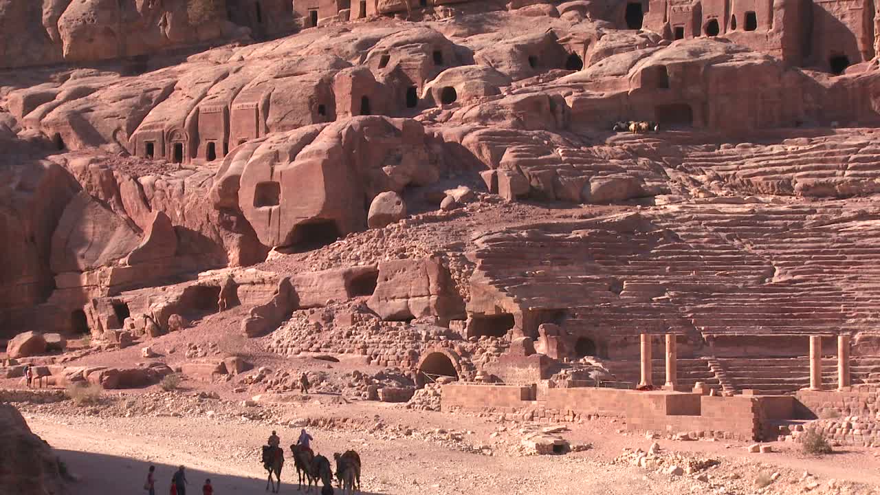 la gente monta burros y camellos cerca del antiguo anfiteatro en las antiguas ruinas nabateas de petra jordan 1
