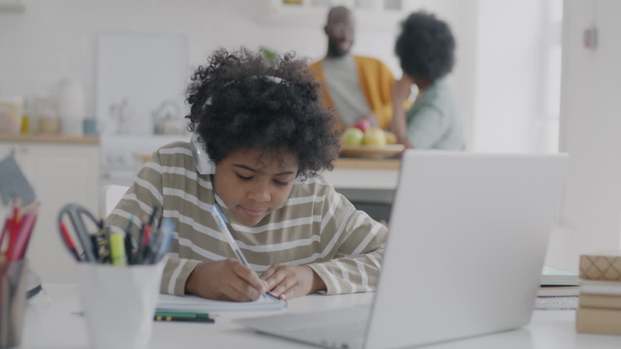 Child Doing Homework at Home with Family in the Background