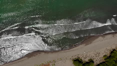 Sandy-beach-washed-by-sea-waves-reflecting-sunlight,-beautiful-sea-texture-with-foaming-water