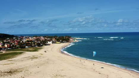 Rotating-aerial-drone-shot-of-kite-surfers-on-the-tropical-Barra-do-Cunhaú-beach-in-Canguaretama-where-the-large-Curimataú-river-meets-the-sea-in-the-state-of-Rio-Grande-do-Norte,-Brazil