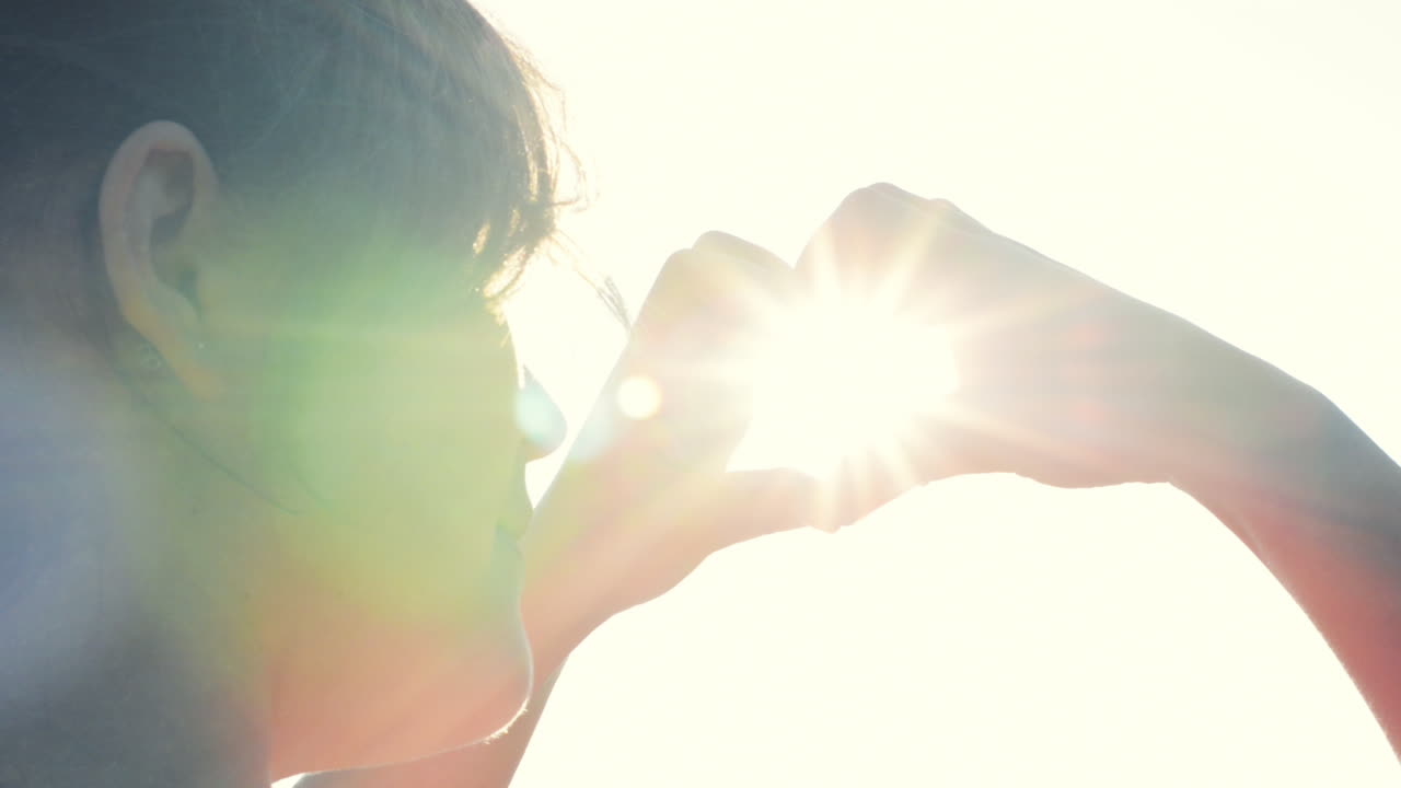 여성의 손은 심장 모양의 몸짓으로  ⁇ 빛을 들고 있습니다.