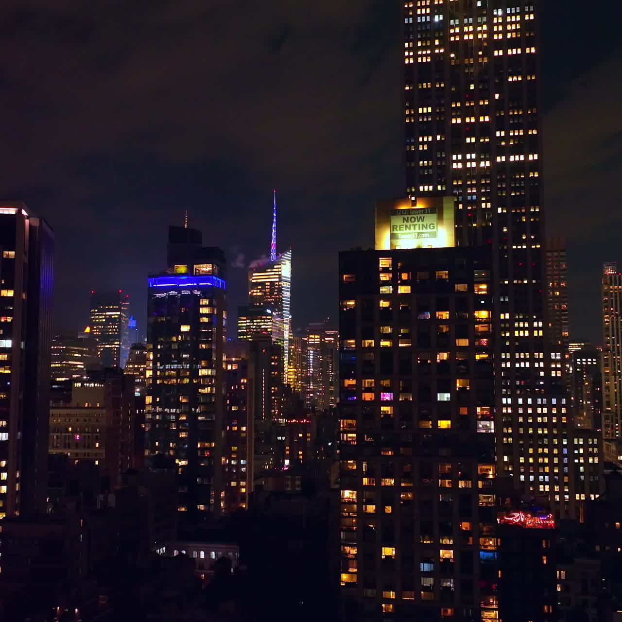 Fantastic skyscrapers with lights in windows. Wonderful buildings at the backdrop of night cloudy sky