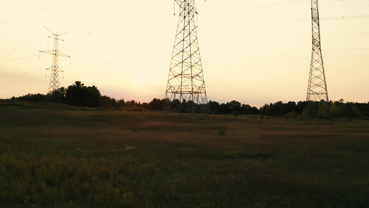 High Voltage Electric Transmission Power Lines Silhouette in Rural Countryside Field
