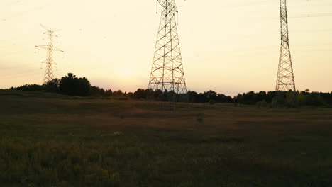 high voltage electric transmission power lines silhouette in rural countryside field