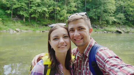 a man with a girlfriend are photographed against the background of a mountain river on a cloudy day