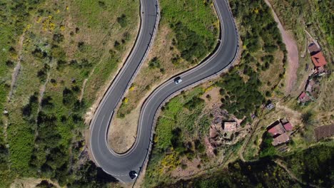 vista aérea cinematográfica de un avión no tripulado mirando hacia abajo en un coche en una carretera sinuosa - gran canaria, españa