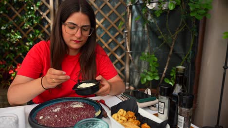 mujer feliz rocía queso en el risotto all'amarone, vista frontal