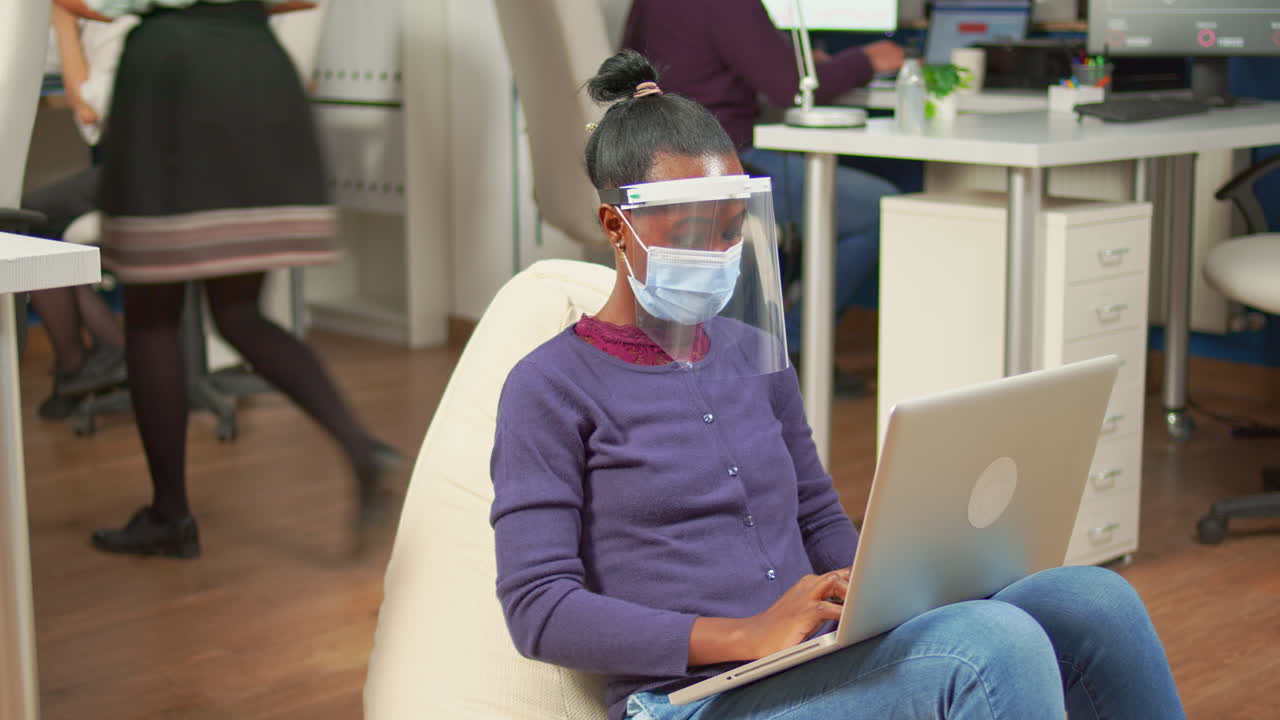 freelancer negro con máscara de protección analizando el proyecto en la computadora portátil