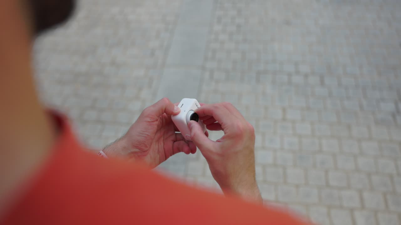 Over The Shoulder View Of Male Detaching Insta360 Go 3 From Action Pod