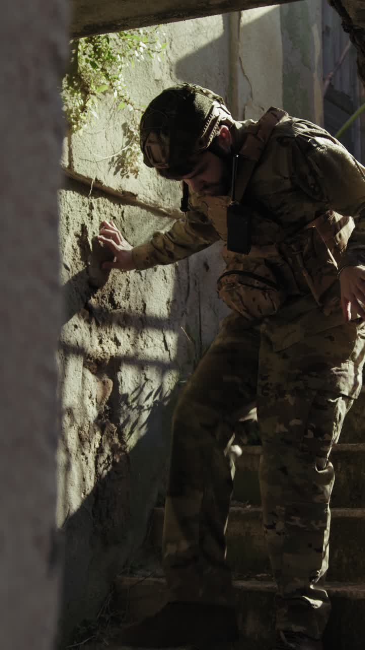 Young Soldier Carefully Goes Down The Stairs Of A Destroyed House