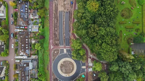 beautiful top down aerial of a new road and roundabout being constructed in a small town with a lot of green trees and parks