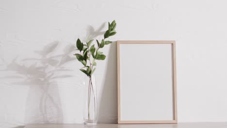 Marco-De-Madera-Con-Espacio-De-Copia-Sobre-Fondo-Blanco-Con-Planta-Contra-Pared-Blanca