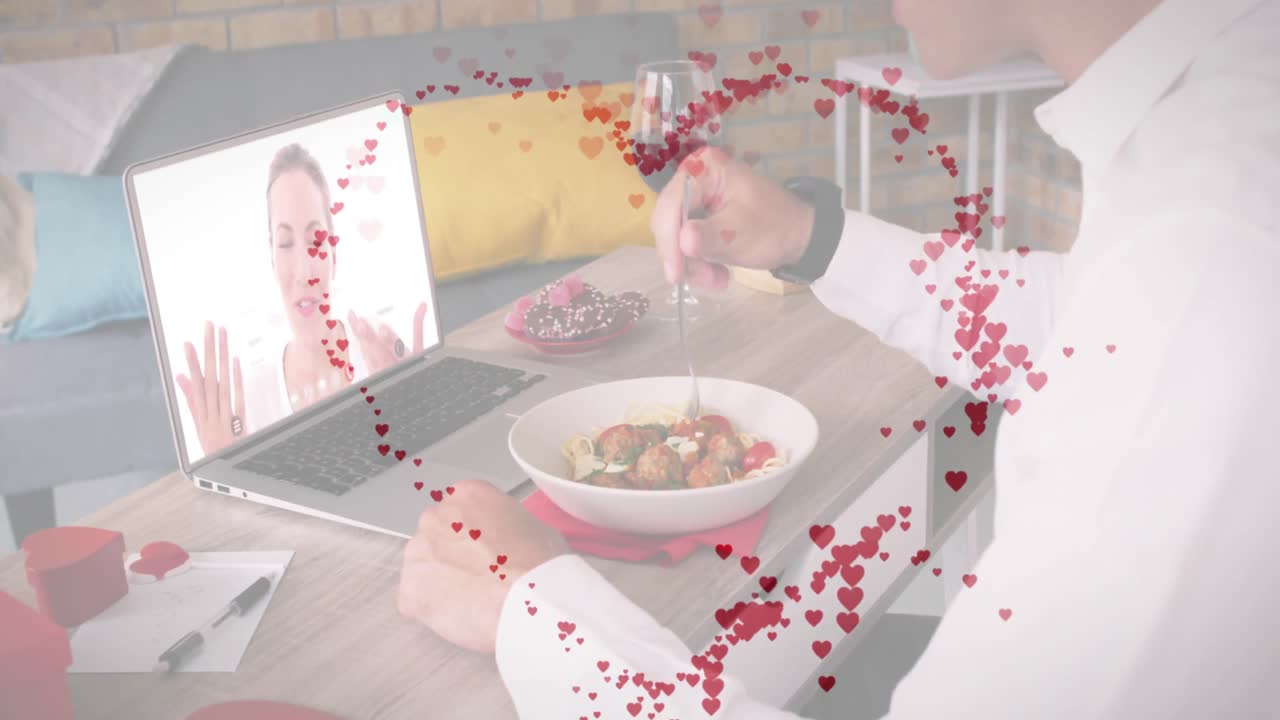 contorno de corazón rojo contra hombre caucásico almorzando mientras tiene una videollamada en una computadora portátil