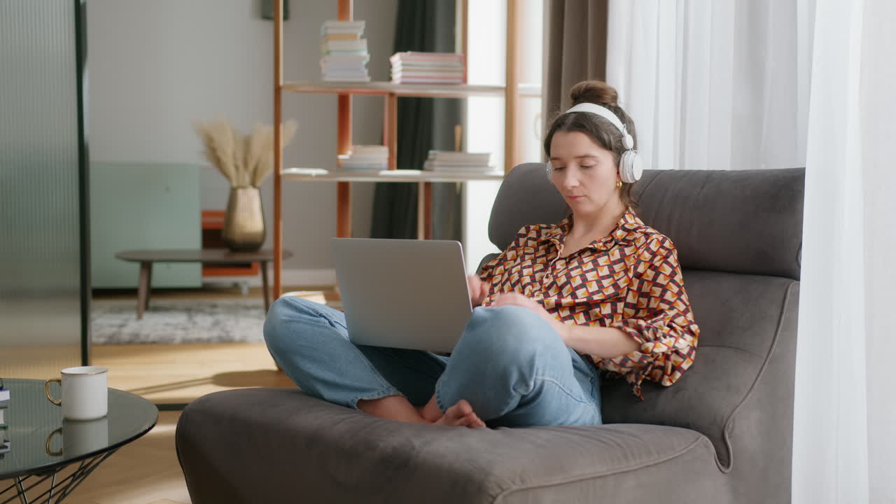 Girl in living room puts on headphones and connects to virtual meeting