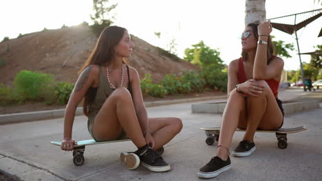 in the soft light of the sunset, two girls on skateboards at the skate park engage in a lively conversation, smiling, and laughter echoing through the air. longboarding and friendly banter