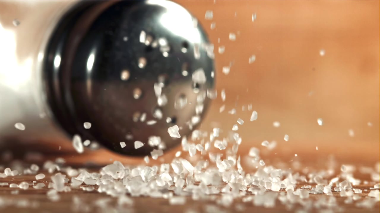 Saltkrystaller falder fra en saltbøsse i slowmotion