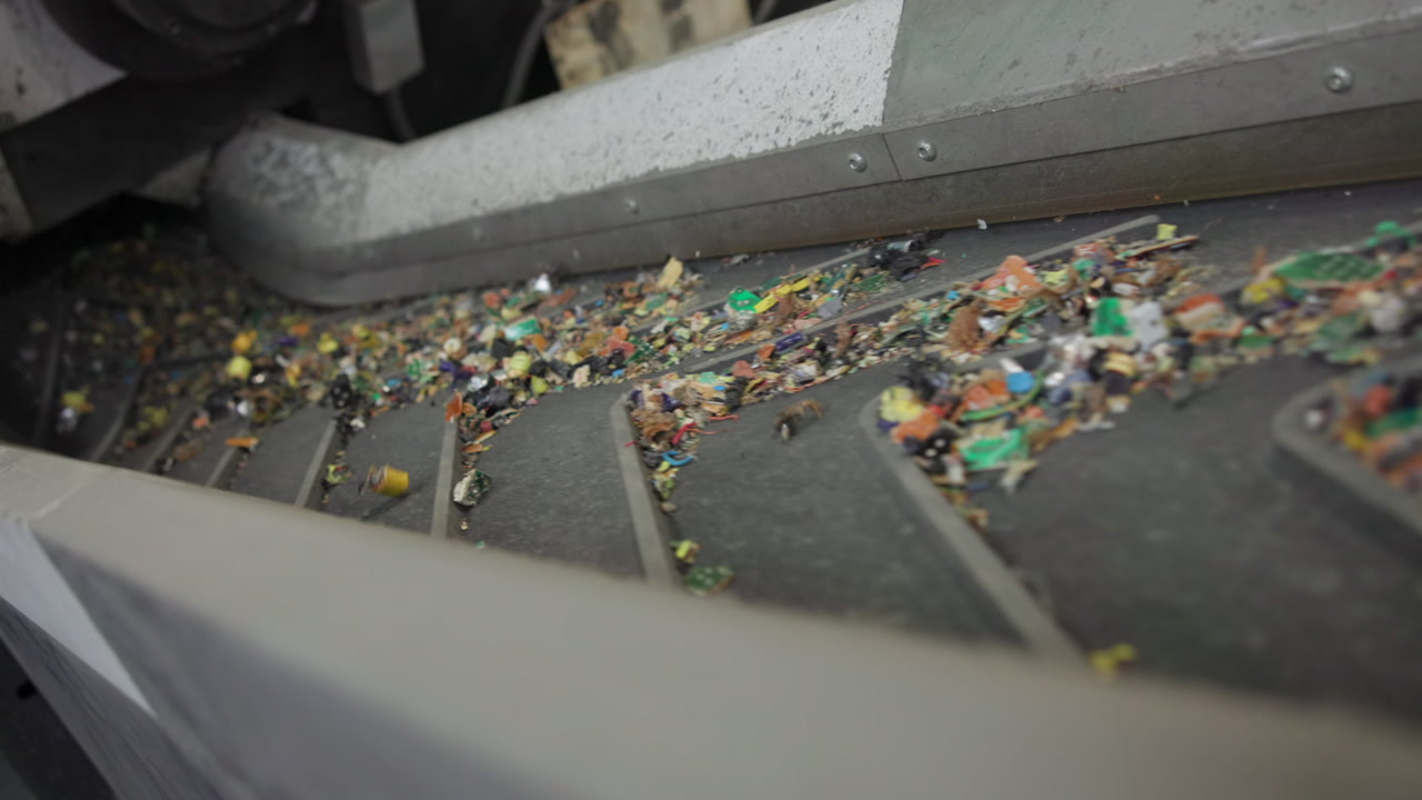 Colorful Plastic Flakes Moving On Conveyor Belt Through Sorting Area, Mixed Polymer Chips Gliding Under Chute, . Media