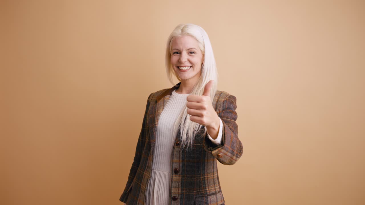 Donna bionda sorridente che fa il gesto del pollice in su