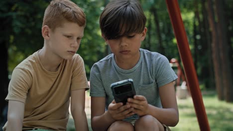 Gruppe-Von-Jungen,-Die-Auf-Dem-Spielplatz-Ihr-Mobiltelefon-Benutzen.