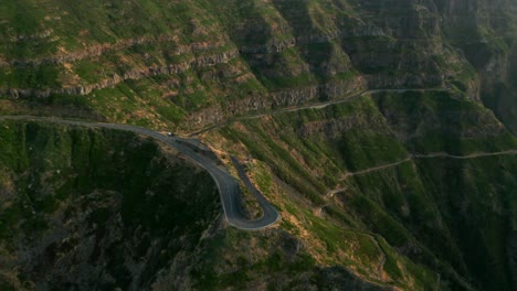 Adventurous-road-on-steep-slope-of-green-volcanic-mountains-during-sunset