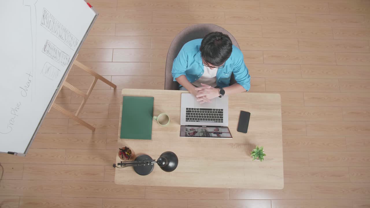 위쪽 뷰  아웃 은 스마트워치 에 노트북에서 회의를 하고 있는 화이트보드 의 나무 책상에 앉아서 손을 흔들고 있는 남자입니다.