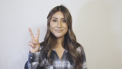 a hispanic woman says the number 2 in multiple different styles and gestures