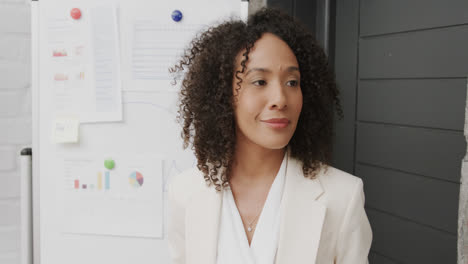 happy biracial businesswoman by whiteboard listening at office meeting, in slow motion