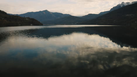 un dron vuela rápidamente inclinándose hacia arriba desde el lago caldonazzo