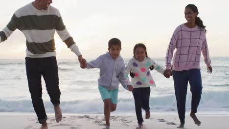 Glückliche-Hispanische-Familie,-Die-Am-Strand-Läuft-Und-Spaß-Bei-Sonnenuntergang-Hat