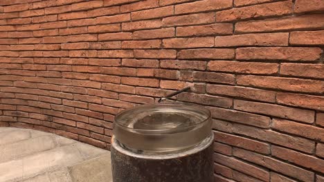 glass jar overflows with water against brick wall