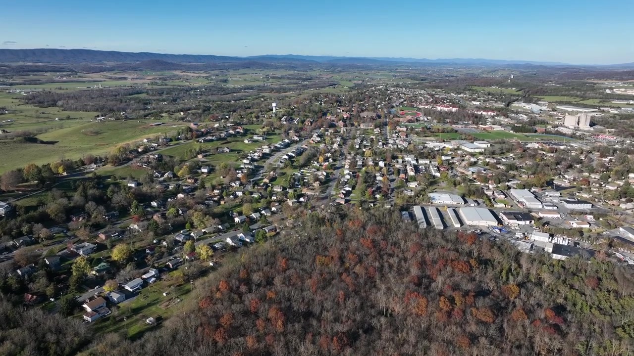 Alberi della foresta colorati in primo piano e piccola città americana sullo sfondo. Case e abitazioni in uno scenario pittoresco degli Stati Uniti. Ripresa aerea dall'alto