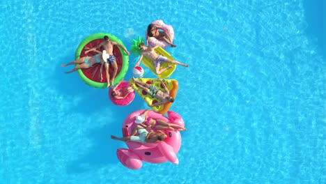 drone: a group of friends hang out at the pool and relax on funny floaties