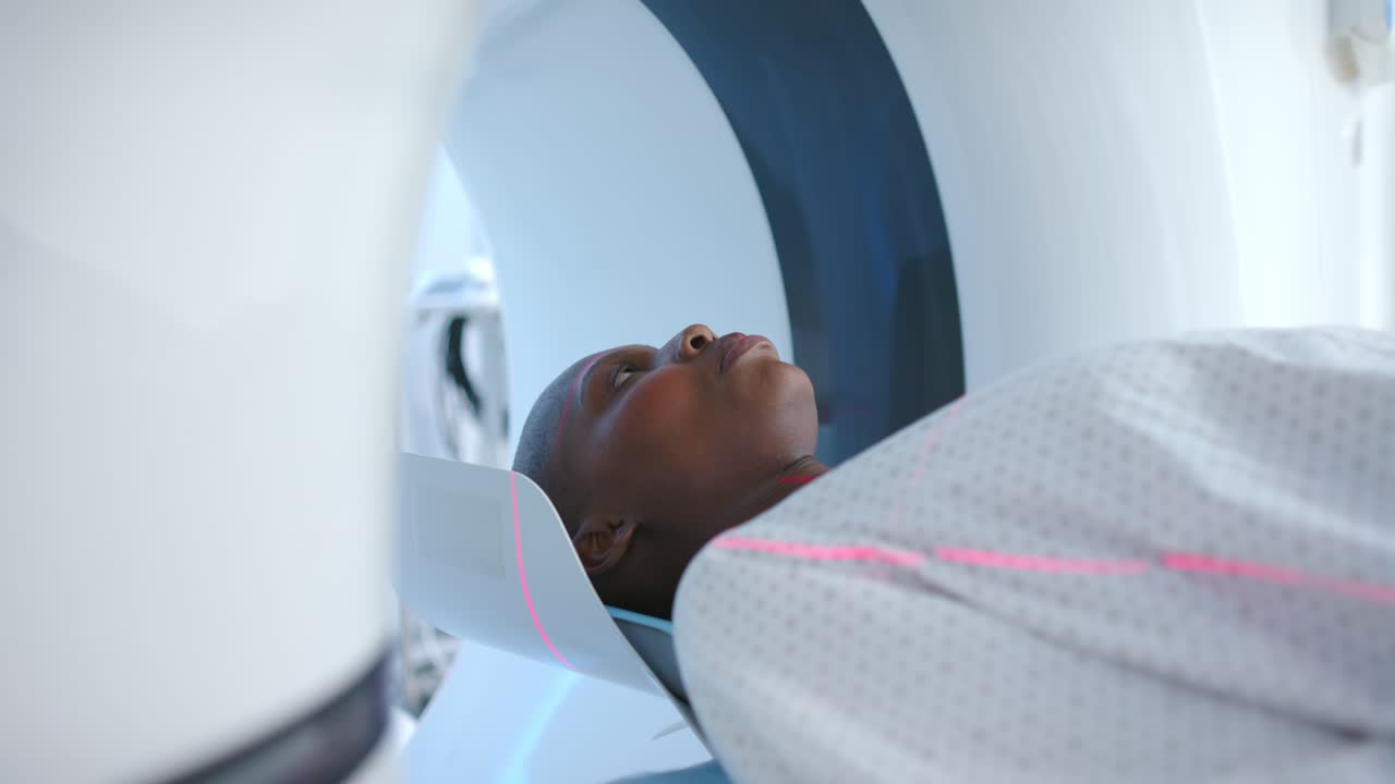 Il tavolo dello scanner si muove all'interno del gantry mentre la macchina inizia la scansione della testa, mostrando laser rosa.