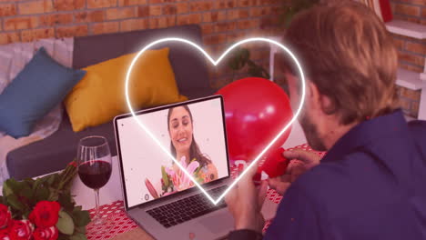 corazón parpadeando contra el neón sobre el hombre caucásico mostrando un anillo mientras tiene una videollamada en la computadora portátil
