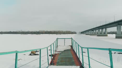 coloured-rusty-pier-at-frozen-river-covered-with-snow