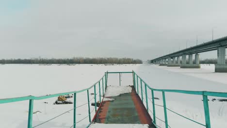 coloured rusty pier at frozen river covered with snow