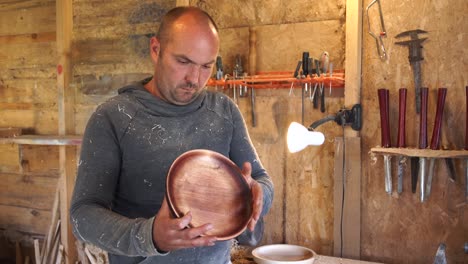 carpenter in sawdust inspects finished product.